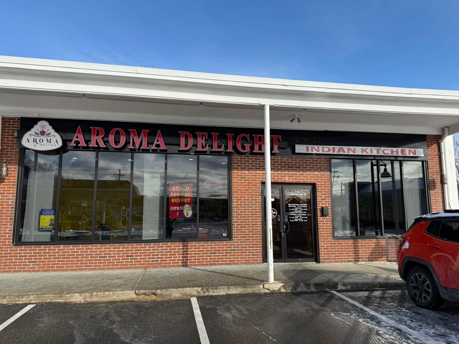 Exterior view of Aroma Delight Indian Kitchen in Burlington, MA, showcasing the restaurant's signage and entrance on a bright winter day